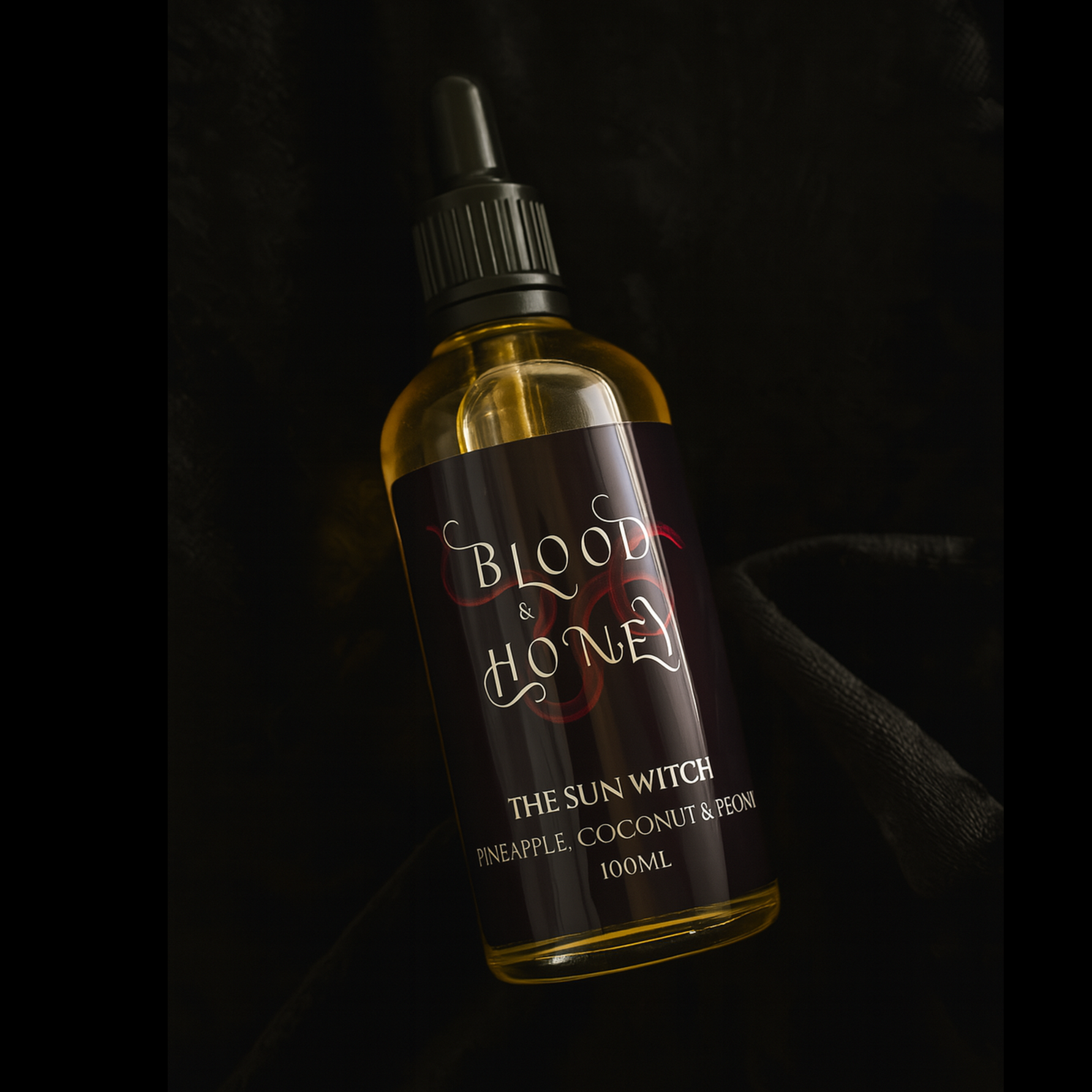Bottle of 'Blood & Honey' The Sun witch body oil, with a dark label on a black background